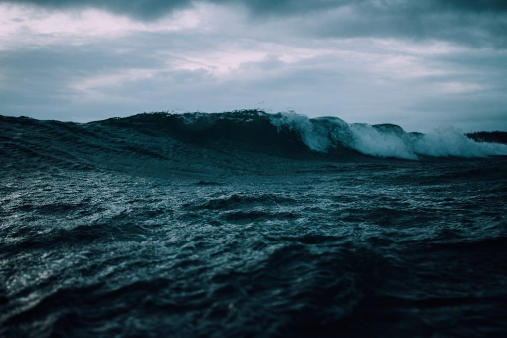 A massive ocean wave crashing under a dark, stormy sky — mirroring the elemental ambition and power of Herman Melville's Moby-Dick