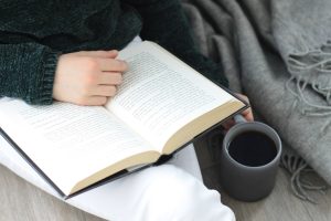 Person reading a novel with a cup of coffee, representing a beginner English reader enjoying their first novel