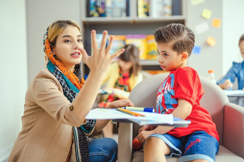 A teacher engaging with a young child one-on-one in a colorful classroom setting