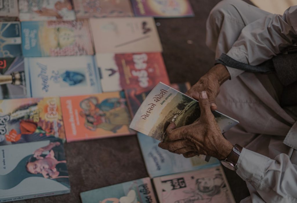 A man browses colourful Urdu and Pakistani storybooks spread on the ground at a street book stall